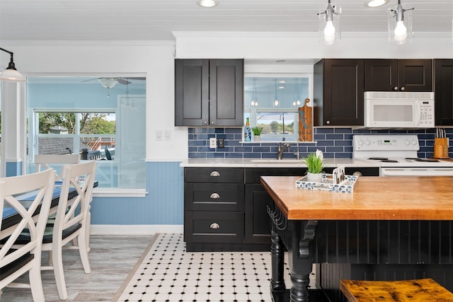 kitchen featuring white appliances, ornamental molding, wooden counters, a sink, and wainscoting