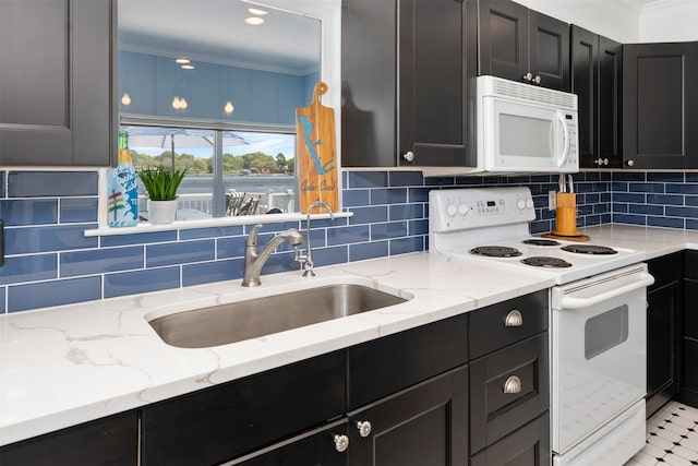 kitchen with white appliances, dark cabinets, and a sink