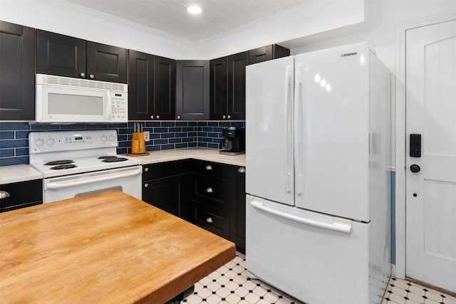 kitchen with light countertops, light floors, dark cabinets, and white appliances