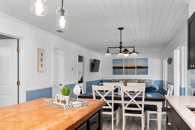 dining room featuring a wainscoted wall, visible vents, wood finished floors, and wooden ceiling