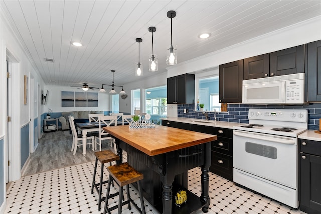 kitchen with white appliances, a kitchen bar, ceiling fan, light hardwood / wood-style flooring, and decorative light fixtures