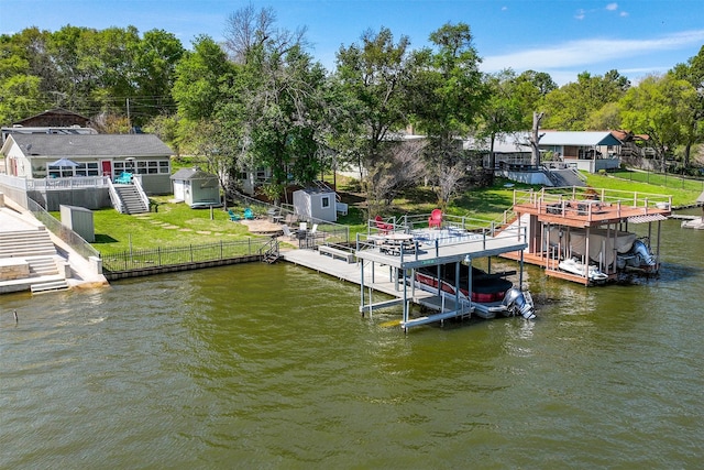 view of dock featuring boat lift, a water view, and a lawn
