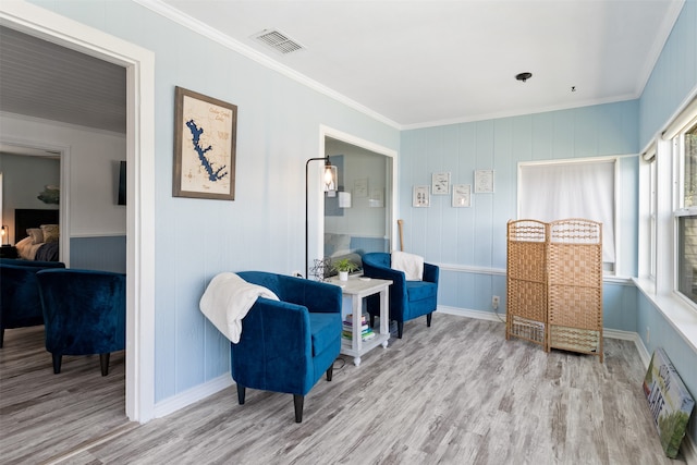 sitting room with light wood-type flooring and ornamental molding