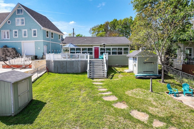 rear view of property featuring stairway, a wooden deck, an outbuilding, a storage unit, and a lawn