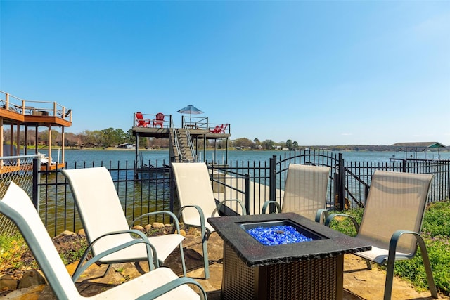 view of patio / terrace featuring a fire pit, a water view, and fence