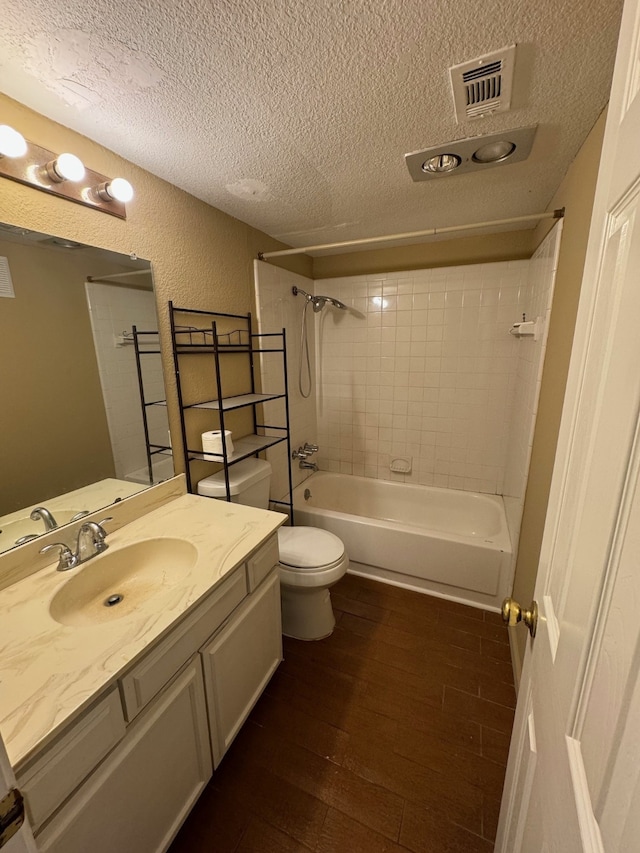 full bathroom featuring vanity, tiled shower / bath combo, a textured ceiling, hardwood / wood-style flooring, and toilet