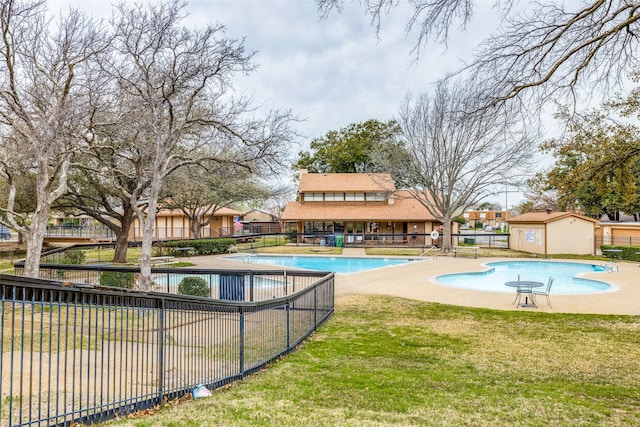 view of pool with a lawn and a storage unit