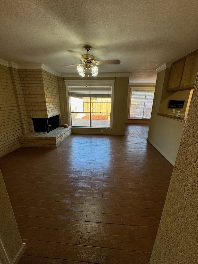 unfurnished living room with ceiling fan, a textured ceiling, a fireplace, and plenty of natural light