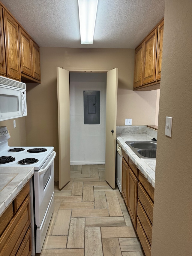 kitchen with a textured ceiling, tile counters, white appliances, and sink