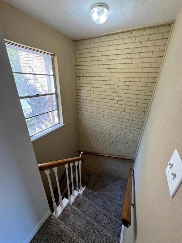 staircase featuring a textured ceiling