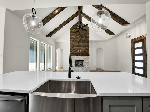 kitchen with lofted ceiling with beams, a fireplace, ceiling fan, and hanging light fixtures