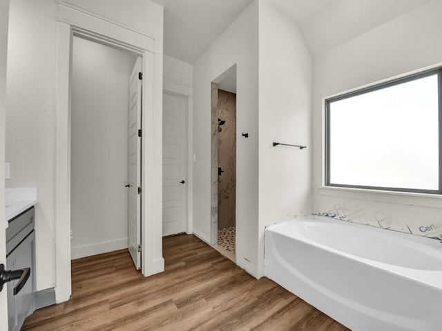 bathroom featuring vanity, separate shower and tub, vaulted ceiling, and hardwood / wood-style flooring