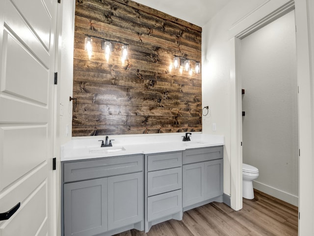 bathroom featuring wooden walls, hardwood / wood-style flooring, vanity, and toilet