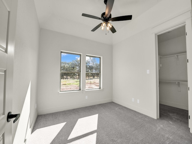 unfurnished bedroom with a spacious closet, light carpet, a closet, and ceiling fan