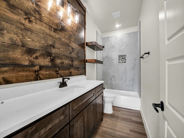 full bathroom featuring tiled shower / bath, vanity, hardwood / wood-style floors, and toilet