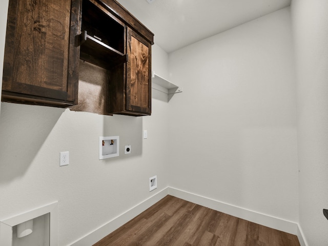 washroom with dark wood-type flooring, hookup for a washing machine, hookup for an electric dryer, and cabinets