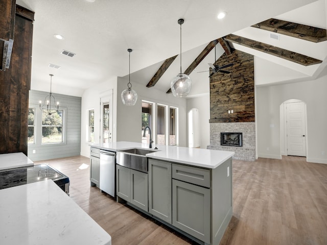 kitchen with gray cabinets, sink, dishwasher, an island with sink, and vaulted ceiling with beams