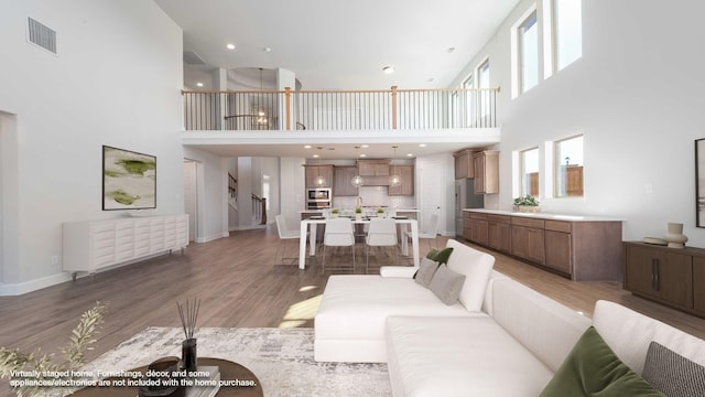 living area with light wood-type flooring, visible vents, baseboards, and stairs