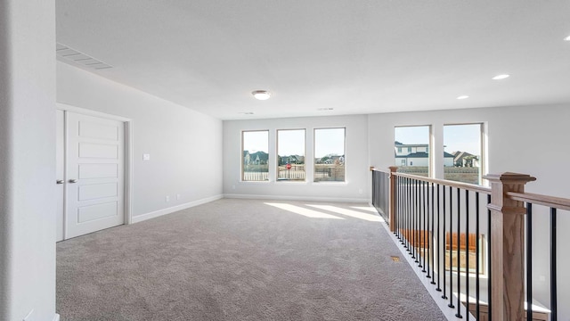 spare room featuring baseboards, carpet, visible vents, and a wealth of natural light