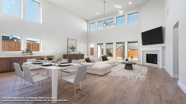 dining space featuring recessed lighting, a fireplace, a ceiling fan, baseboards, and light wood-type flooring