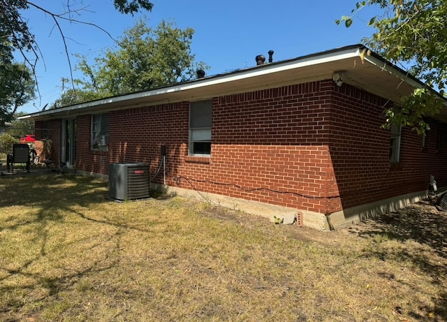 view of side of property featuring a lawn and central AC