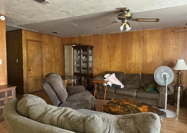 living room with wood walls, ceiling fan, and light hardwood / wood-style flooring