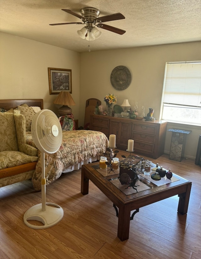 living room featuring wood-type flooring, ceiling fan, and a textured ceiling