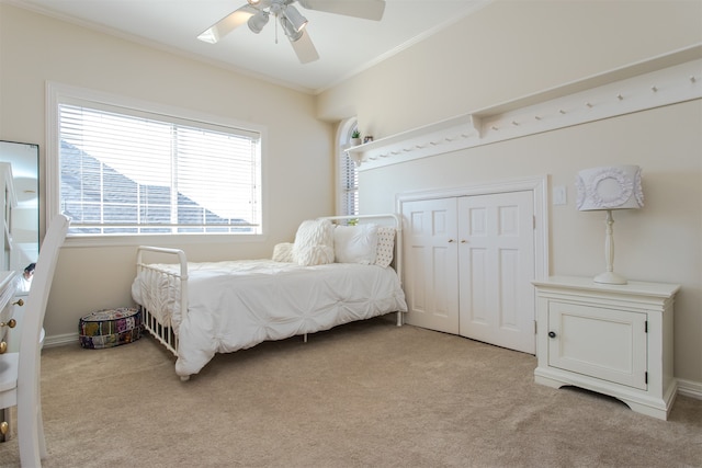 carpeted bedroom with a closet, ceiling fan, and crown molding