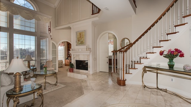 living room featuring crown molding, a high ceiling, and a high end fireplace