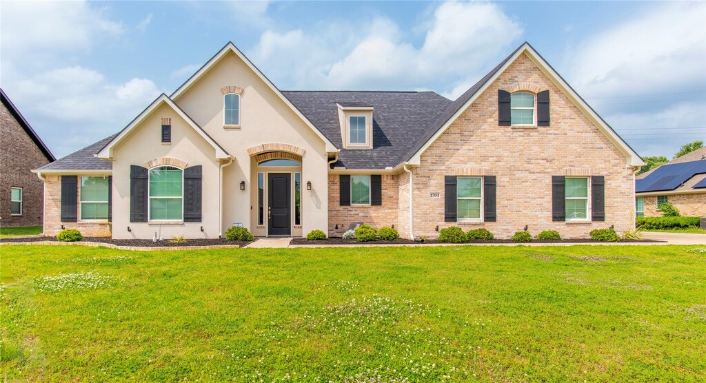 1304 Madeline St, Commerce, TX 75428 - view of front facade with brick siding, roof with shingles, and a front lawn