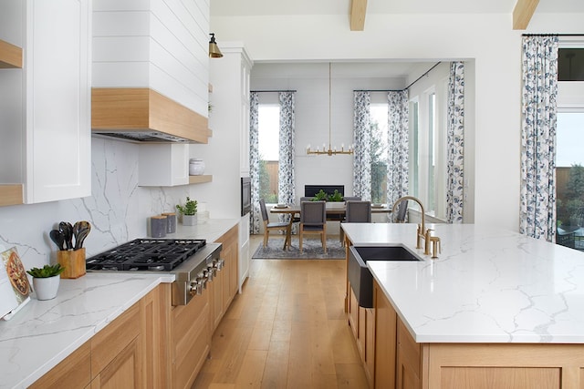 kitchen featuring light stone counters, stainless steel gas cooktop, light hardwood / wood-style flooring, custom exhaust hood, and sink