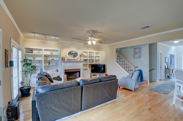 living room with crown molding, track lighting, ceiling fan, and light hardwood / wood-style flooring