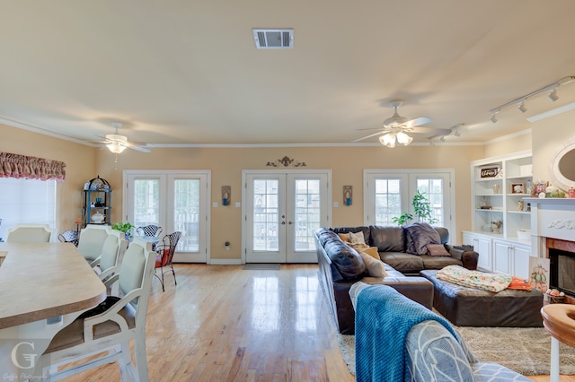 living room with ceiling fan, french doors, track lighting, crown molding, and light hardwood / wood-style floors