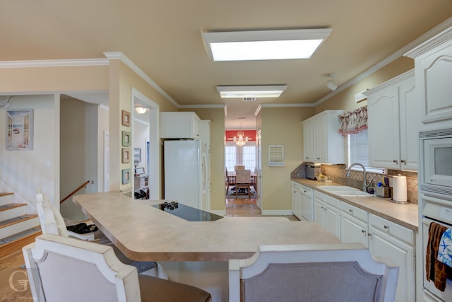 kitchen featuring a chandelier, sink, white cabinetry, white appliances, and ornamental molding