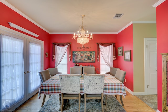 dining space featuring a notable chandelier, light hardwood / wood-style flooring, and crown molding