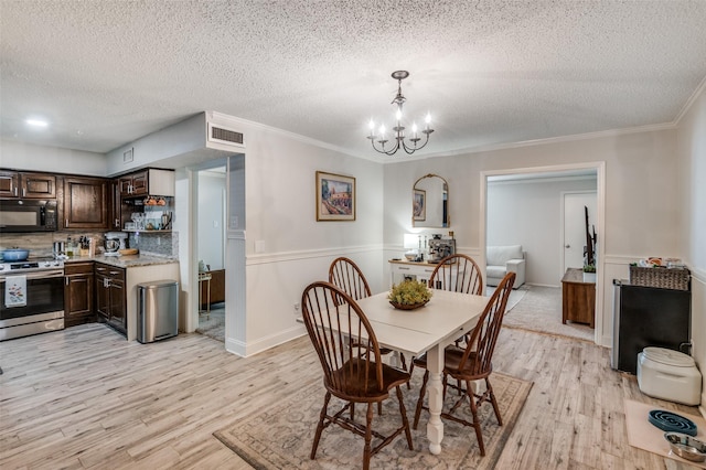 dining space with a notable chandelier, crown molding, a textured ceiling, and light hardwood / wood-style flooring