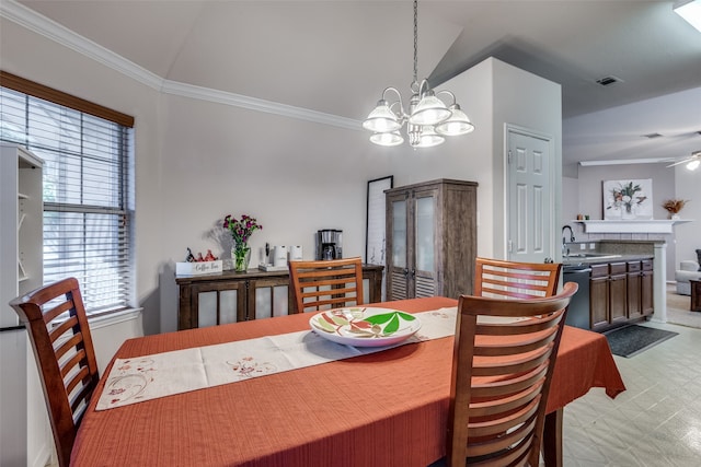 dining room featuring sink, ceiling fan with notable chandelier, lofted ceiling, a fireplace, and crown molding