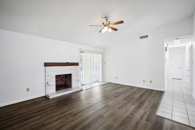 unfurnished living room with a fireplace, vaulted ceiling, dark hardwood / wood-style flooring, and ceiling fan