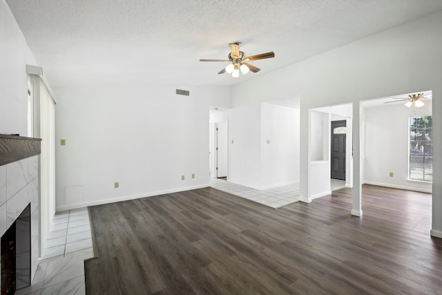 unfurnished living room with ceiling fan, a textured ceiling, a fireplace, and dark wood-type flooring