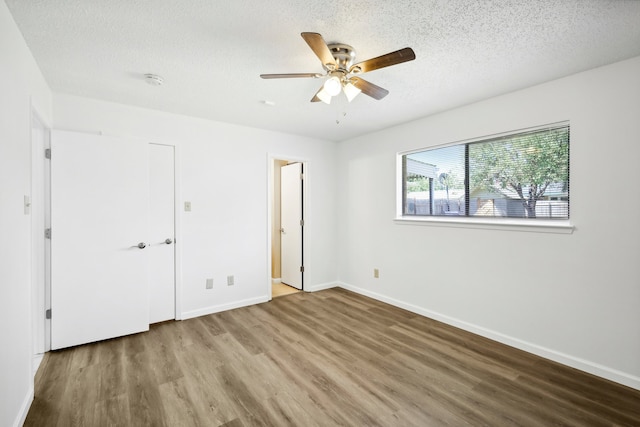 unfurnished bedroom featuring ceiling fan, hardwood / wood-style flooring, and a textured ceiling