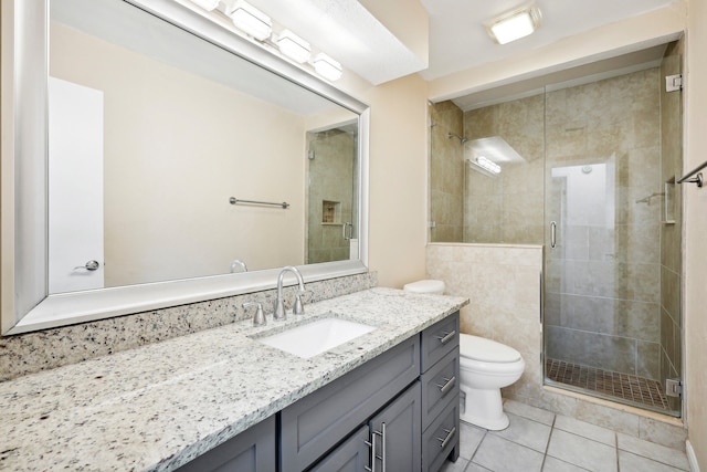 bathroom featuring tile walls, tile patterned floors, a shower with shower door, vanity, and toilet