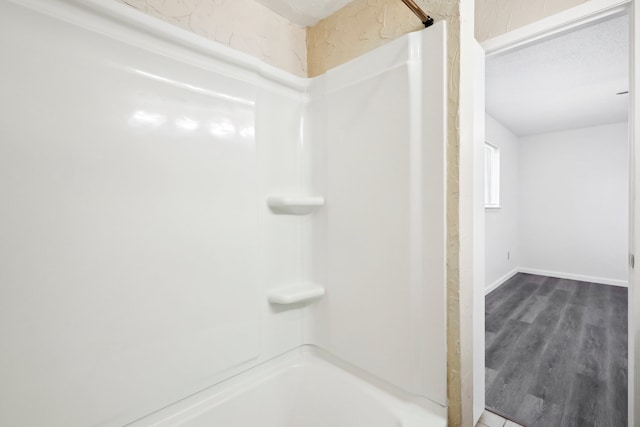 bathroom featuring a textured ceiling, shower / bathtub combination, and hardwood / wood-style floors