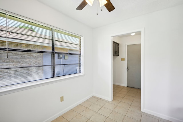 empty room featuring light tile patterned floors, ceiling fan, and a wealth of natural light