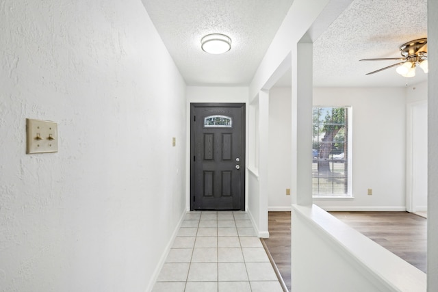 foyer entrance featuring light wood-type flooring, a textured ceiling, and ceiling fan