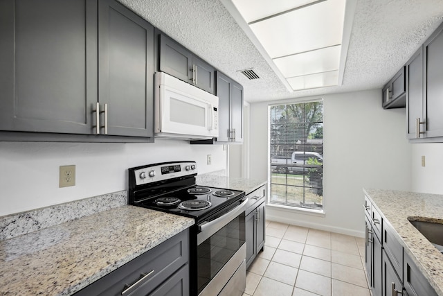 kitchen with gray cabinets, light stone counters, a textured ceiling, stainless steel electric range oven, and light tile patterned floors