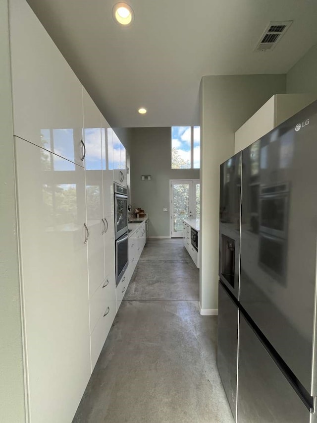 kitchen featuring refrigerator with ice dispenser, white cabinetry, and double oven