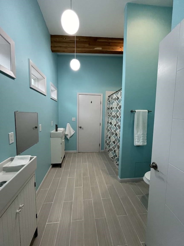 bathroom featuring beamed ceiling, vanity, toilet, hardwood / wood-style floors, and a shower with shower curtain