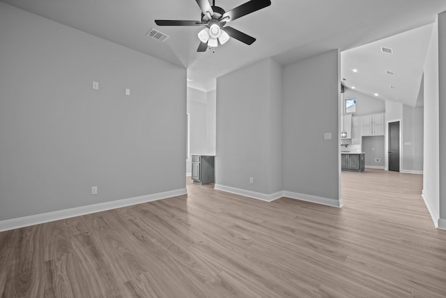 unfurnished living room with ceiling fan, lofted ceiling, and light wood-type flooring