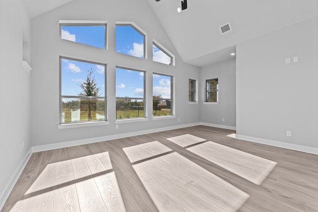 unfurnished living room featuring high vaulted ceiling and light hardwood / wood-style floors