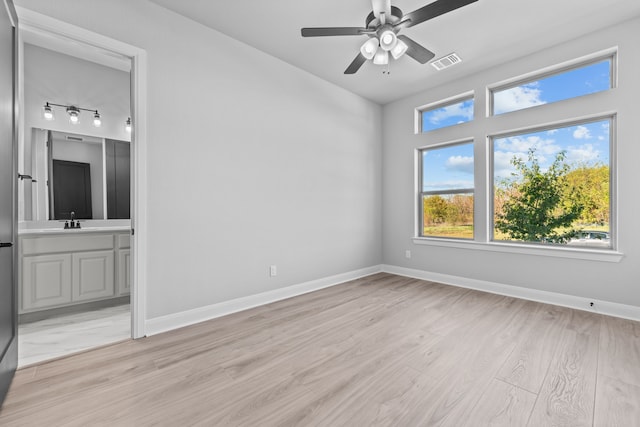 empty room featuring sink, ceiling fan, and light wood-type flooring